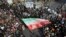 In this photo provided by Tasnim News Agency, a demonstrator waves a huge Iranian flag during a pro-government rally in the northeastern city of Mashhad, Iran, Jan. 4, 2018.