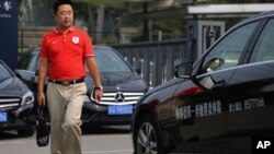 A man walks past Mercedes-Benz cars parked outside the dealer sales showroom in Beijing, China, Aug. 18, 2014. 