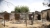 A woman stands in front of a burnt building in Michika town, after the Nigerian military recaptured it from Boko Haram, in Adamawa state, May 10, 2015.