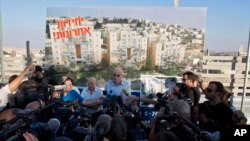 Israeli Minister of Housing and Construction Uri Ariel (C) speaks to journalists during a ceremony to mark the resumption of the construction of housing units in an east Jerusalem neighborhood, August 11, 2013.