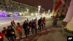 FILE - People carry candles to the Belarusian state security service, KGB headquarters in the center of Minsk, Belarus, Sept. 28, 2021. The Belarusian Ministry of Information on Wednesday blocked access to the Komsomolskaya Pravda in Belarus website.