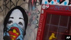 A mother and her child are reflected as they pass a mural by artist FAKE, titled "Super Nurse," paying tribute to all health care and medical professionals in times of the coronavirus, in Amsterdam, Netherlands, April 19, 2020.