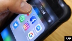 រូបឯកសារ៖ បុរសម្នាក់​កាន់​ទូរស័ព្ទ​ទំនើប​ដែល​មាន​រូបតំណាង​សម្រាប់​កម្មវិធី​បណ្តាញ​សង្គម​ដូចជា ហ្វេសប៊ុក Instagram និង Twitter នៅ​ថ្ងៃទី២៣ ខែមីនា ឆ្នាំ ២០១៨។