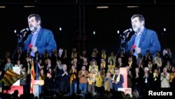 FILE - A picture of jailed activist Jordi Sanchez appears on a screen as a recording by him is played during a meeting of his political platform in Barcelona, Spain, Dec. 15, 2017.
