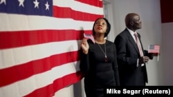 Deux Américains nouvellement naturalisés posent à côté d'un drapeau américain après avoir prêté serment lors d'une cérémonie spéciale au bureau des services de citoyenneté et d'immigration des États-Unis (USCIS) à Manhattan, New York, le 13 novembre 2015. REUTERS/Mike Segar