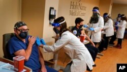 FILE - Staff members receive the COVID-19 vaccine at Holy Name Medical Center in Teaneck, N.J., Dec. 17, 2020.