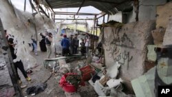 Warga setempat memeriksa lokasi pasca serangan bom bunuh diri di pasar yang ramai di kota Sadr, Irak, 2 Januari 2016. (AP Photo/ Karim Kadim).