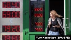 RUSSIA -- A woman leaves exchange office with an electronic panel displaying currency exchange rates for the U.S. dollar and the euro against the Russian ruble in Moscow, August 23, 2018.