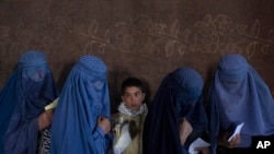 FILE - Afghan women wait to receive cash at a money distribution point organized by the World Food Program, in Kabul, Afghanistan, on Nov. 20, 2021. 