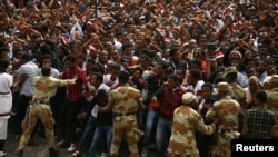 FILE - Demonstrators chant slogans while flashing the Oromo protest gesture during Irreecha, the thanksgiving festival of the Oromo people, in Bishoftu town, Oromia region, Ethiopia, Oct. 2, 2016.
