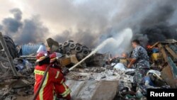 Firefighters spray water on a fire following an explosion in Beirut's port area, Lebanon, Aug. 4, 2020. 