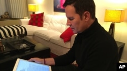 Juan Carlos Cruz reads from his tablet during an interview with The Associated Press in Philadelphia, Feb. 4, 2017.