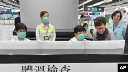 Hong Kong Chief Executive Carrie Lam, second from right, and Secretary for Food and Health, Prof. Sophia Chan, right, reviews the health surveillance by officers of the Port Health Division at West Kowloon Station in Hong Kong, Jan. 3, 2020.