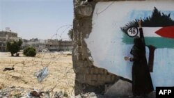 Một phụ nữ Palestine sơn graffiti cờ Palestine lên một bức tường ở Gaza City, thứ năm 6 tháng năm, 2010