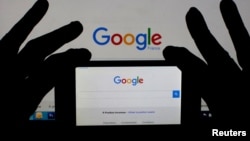 FILE - A woman holds her smartphone, which displays the Google homepage, Feb. 24, 2016. 
