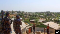 FILE - A security officer makes announcements on a megaphone for people to observe social distancing at Kutupalong Rohingya camp bazar in Cox's Bazar, Bangladesh, May 15, 2020. 