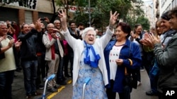 FILE, In this Sunday, Oct. 1, 2017 photo, an elderly lady is applauded as she celebrates after voting at a school assigned to be a polling station by the Catalan government at the Gracia neighborhood in Barcelona, Spain. (AP Photo/Bob Edme, File)