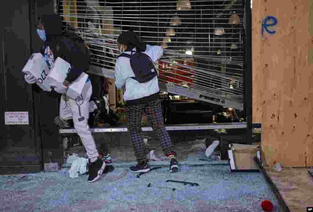 People exit damaged stores after the glass was knocked out in the Chelsea neighborhood of New York, June 1, 2020.