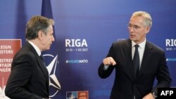 Menlu AS Antony Blinken (kiri) dan Sekjen NATO Jens Stoltenberg bertepuk tangan saat mereka memberikan konferensi pers selama pertemuan para menteri luar negeri NATO di Riga, Latvia pada 30 November 2021. (Foto: AFP)