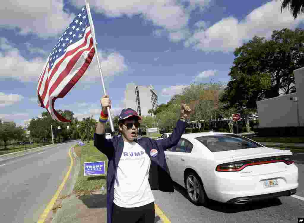 Pablo Ramos, a Donald Trump supporter, stands in the middle of Orange Avenue waving a flag and cheering to passing motorists that toot their horns in Orlando, Florida.