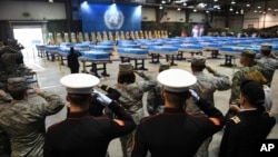 1일 한국 평택시 오산공군기지에서 북한에서 돌려받은 한국전쟁 참전 미군 유해 송환식이 열린 가운데, 군인들이 유해가 담긴 55개의 금속관을 향해 경례하고 있다. 