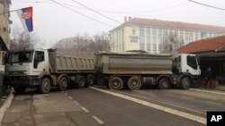 A man passes by a barricade made of trucks loaded with stones that was erected during the night on a street in northern, Serb-dominated part of ethnically divided town of Mitrovica, Kosovo, Dec. 27, 2022.