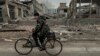 Seorang pria mengendarai sepeda di depan kantor pos yang hancur akibat serangan udara Rusia di Kurakhove, wilayah Donetsk, Ukraina, pada 7 November 2024. (Foto AP/Anton Shtuka)
