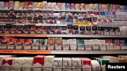 FILE - Cigarette packs are seen on shelves in a tobacco shop in Cagnes-sur-Mer, France, Sept. 8, 2015. The World Health Organization on Tuesday called on countries do adopt plain packaging to make tobacco products less attractive and reduce deaths from smoking.