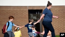 Kids are led to Blue Ridge Elementary School for the first day of classes in Evans, Ga., Monday morning, Aug. 3, 2020. (Michael Holahan/The Augusta Chronicle via AP)