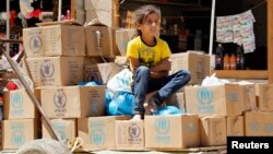 A Syrian refugee girl sits on humanitarian aid boxes, received by her father at Al Zaatri refugee camp in the Jordanian city of Mafraq, near the border with Syria, Sept. 8, 2013.