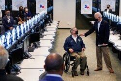 President Joe Biden talks with Texas Gov. Greg Abbott as they tour the Harris County Emergency Operations Center, Feb. 26, 2021, in Houston.