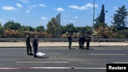 Seorang polisi dan tentara Israel memeriksa lokasi jatuhnya proyektil, setelah kelompok bersenjata Lebanon, Hizbullah, mengatakan telah meluncurkan segerombolan pesawat nirawak serang terhadap target militer di Israel utara, di Nahariya.