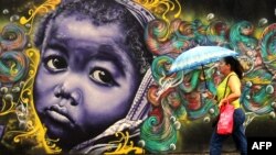 A woman passes by a graffiti in Salvador da Bahia, Brazil, June 18, 2013. 