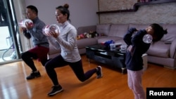 Dino Lin, Stella Zhang and Wowo Lin, 5, exercise using filled water bottles as weights as they watch a fitness class online at their house, during the novel coronavirus disease (COVID-19) outbreak, in Shanghai, China, February 25, 2020. 