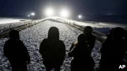 Military veterans stand on a bridge across from police protecting the Dakota Access oil pipeline site in Cannon Ball, N.D., Dec. 1, 2016.