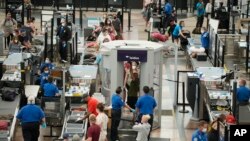 FILE - Travelers wear face coverings in the line for the south security checkpoint in the main terminal of Denver International Airport on Aug. 24, 2021, in Denver.