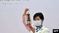 Tokyo Governor Yuriko Koike holds the Olympic flame during its unveiling ceremony at the Komazawa Olympic Park General Sports Ground, in Tokyo, July 9, 2021. 