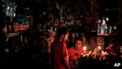 Seorang pemilik toko di Dhaka berinteraksi dengan pembeli dalam kegelapan akibat padamnya listrik selama 12 jam di seluruh Bangladesh (1/11). (AP/A.M. Ahad)