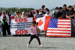 Afghan migrants take part in a rally outside the U.S. Embassy in Bishkek, Kyrgyzstan, Aug. 19, 2021, requesting Kyrgyz citizenship or resettlement to the U.S. or Canada.