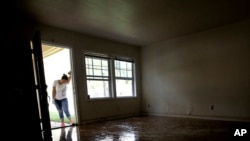 FILE - In this Aug. 31, 2017 file photo, Alejandra Castillo takes a break from carrying water-soaked items out of her family's home after flood waters receded in Houston. Experts say Harvey’s filthy floodwaters pose significant dangers to human safety and the environment that will remain even after levels drop far enough that southeastern Texas residents no longer fear for their lives.