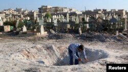 26일 시리아 정부군의 공습으로 생긴 것으로 추정되는 구덩이를 한 남성이 살펴보고 있다. 