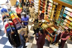 A volunteer of District Magistrate (DM) office dressed as Yamraj, or Hindu God of death, and Civil Defense officers fine people for not wearing masks inside a shop in New Delhi, India, Sept. 28, 2020.