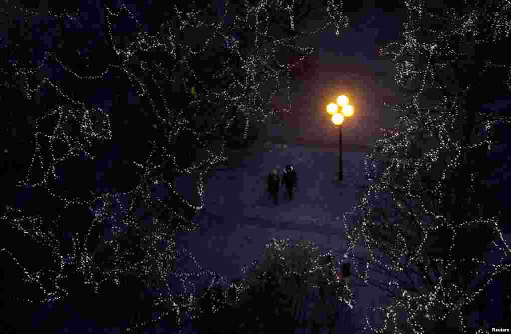 People walk under trees decorated with Christmas lights as the traditional Christmas market opens at the Old Town Square in Prague, Czech Republic, Nov. 26, 2016.