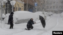 Seorang pria terpeleset dan jatuh menyeberang jalan saat hujan salju lebat di Madrid tengah, Spanyol, Sabtu, 9 Januari 2021. (AP Photo/Paul White)