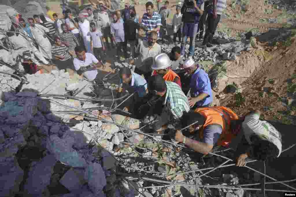 Palestinians search for victims under the rubble of a house that witnesses said was destroyed by an Israeli air strike east of Khan Younis in the southern Gaza Strip, July 24, 2014. 
