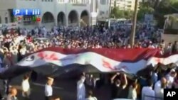 Image from amateur video made available by Shamsnn on August 30, 2011 shows protesters carrying a large Syrian flag with the words "Freedom, Syria" written on it in Arabic in Idlib. (The contents of this image cannot be independently verified)