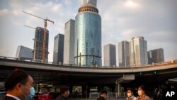 People wearing face masks to protect themselves against the spread of the new coronavirus cross an intersection in the central business district in Beijing, Friday, April 17, 2020. China faces a drawn-out struggle to revive an economy that suffered…