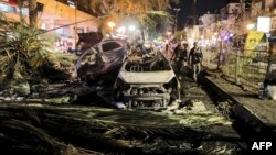 កងកម្លាំង​សន្តិសុខ​អ៊ីស្រាអែល ដើរក្បែរ​រថយន្ត​ដែល​រង​ការខូចខាត​នៅក្នុង​ក្រុង Holon ក្បែរ​ទីក្រុង Tel Aviv នៅ​ថ្ងៃទី១១ ខែឧសភា ឆ្នាំ២០២១ ក្រោយពី​គ្រាប់រ៉ុក្កែត​ត្រូវបាន​បាញ់ឆ្ពោះ​ទៅកាន់​អ៊ីស្រាអែល​ពី​តំបន់ Gaza Strip ដែល​គ្រប់គ្រង​ដោយ​ចលនា​ក្រុម Hamas ប៉ាឡេស្ទីន។