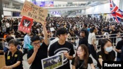 FILE - Anti-extradition bill protesters hold up placards for arriving travelers during a protest at the arrival hall of Hong Kong International Airport in Hong Kong, China, Aug. 9, 2019. 