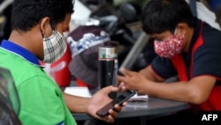 រូបឯកសារ៖ បុរសពីរនាក់ដែលមានពាក់ម៉ាស់ដើម្បីការពារការឆ្លងជំងឺកូវីដ១៩ កំពុងប្រើប្រាស់ប្រព័ន្ធអ៊ីនធឺណិតតាមទូរស័ព្ទស្មាតហ្វូន នៅរាជធានីភ្នំពេញ កាលពីថ្ងៃទី១៨ ខែមីនា ឆ្នាំ២០២០។